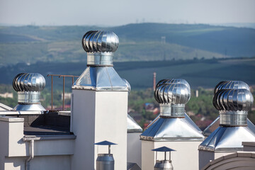 Roofs and chimneys of a modern house . Wind Driven Turbines , rotation creates pressure zone...