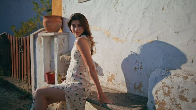 Sexy woman squinting sun resting old village bench. Romantic lady touching hair