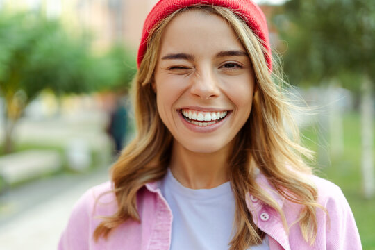 Portrait of attractive woman wearing stylish red hat looking at camera standing on the street, closeup