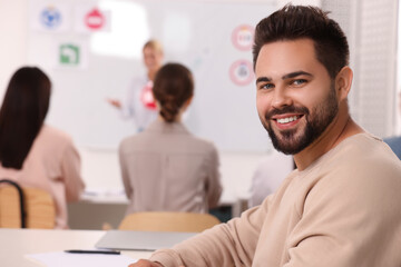 Happy man at desk in class during lesson in driving school. Space for text