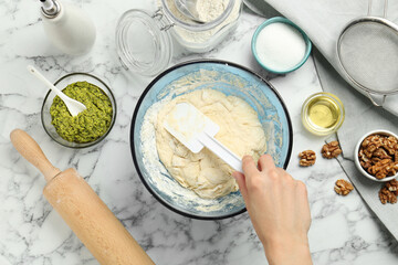Preparing delicious pesto bread. Woman making dough at white marble table, top view