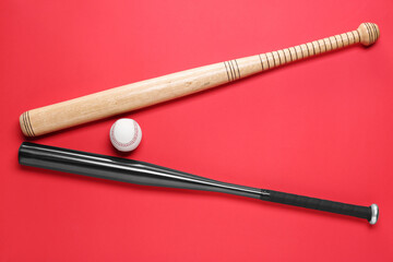 Baseball bats and ball on red background, flat lay