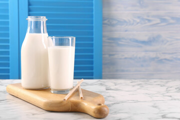 Glassware with tasty milk and straws on white marble table, space for text