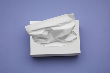 Box of paper tissues on purple background, above view