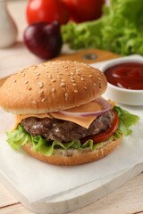 Tasty hamburger with patty, cheese and vegetables on light table