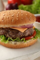 Tasty hamburger with patty, cheese and vegetables on light table, closeup
