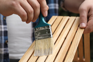 Man applying varnish onto wooden crate, closeup
