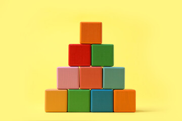 Pyramid of blank colorful cubes on yellow background
