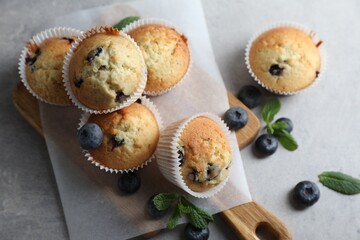 Delicious sweet muffins with blueberries and mint on grey table, flat lay