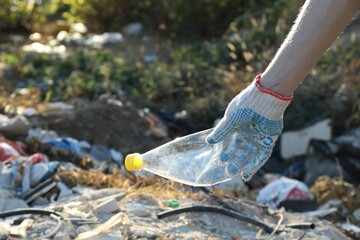 Woman picking up plastic garbage outdoors, closeup