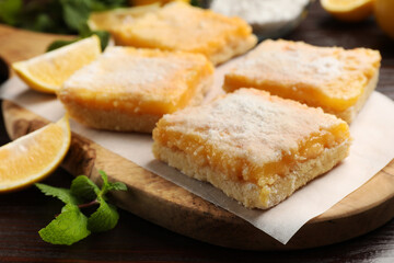 Tasty lemon bars with powdered sugar and mint on table, closeup