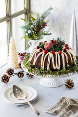 A beautifully decorated chocolate bundt cake next to a bright window.