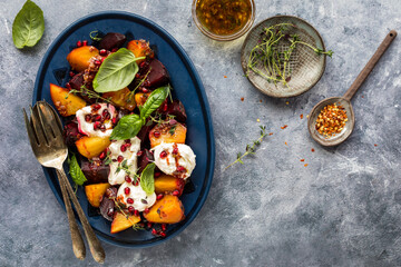 A platter of roasted beets with burrata cheese topped with herbs and pomegranate