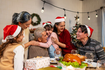 Asian kid hugging grandparent while celebrate Christmas party in house. 