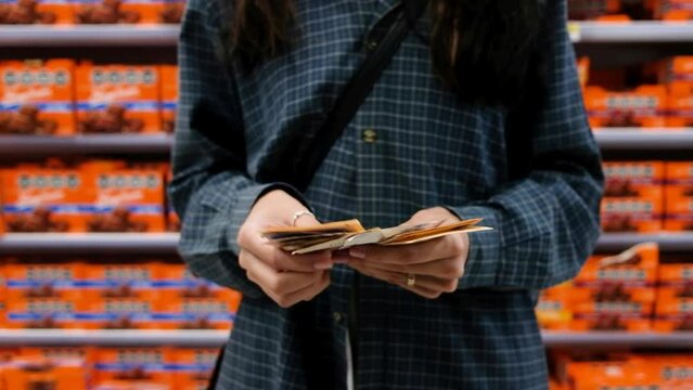 Woman counting money -Argentine pesos- in the supermarket.