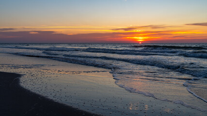 Sunr Rises on Right over Beach with Reflections on Wet Sand