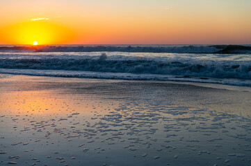 Obraz premium Beach Sunrise with reflection on sand and Sea foam (sun on left)