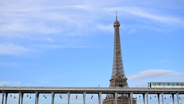 Paris, France - July 9, 2023 : day view of the parisian urban subway (metro, metropolitain) passes over a bridge (pont de Bir-Hakeim Passy line 6) with the Eiffel Tower (Tour Eiffel) in the background