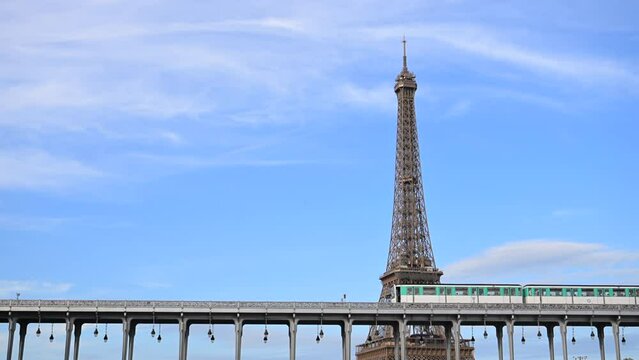 Paris, France - July 9, 2023 : day view of the parisian urban subway (metro, metropolitain) passes over a bridge (pont de Bir-Hakeim Passy line 6) with the Eiffel Tower (Tour Eiffel) in the background