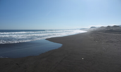 Khalaktyrsky Black sand beach scenic panorama with distant mountains on sunny day, Kamchatka famous travel destination