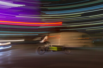 fast moving motion photo of a person riding a bicycle at night in busy traffic