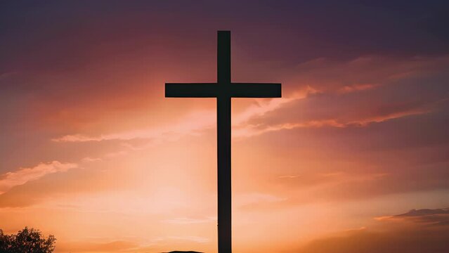 Concept photo of a cross silhouette, standing tall on the horizon as the sun sets behind it. The vibrant oranges and pinks of the sky reflect the warmth and comfort that faith can bring to