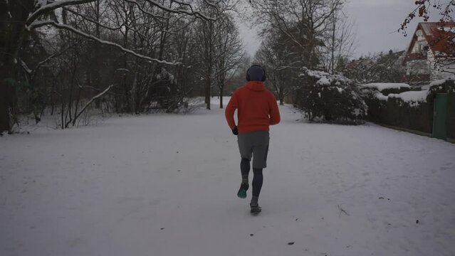 Topic of the right equipment and footwear for winter training outdoors. Runner slides on slippery snowy surface while jogging outside in winter. Sneakers slipping while running. Sleazy road. 