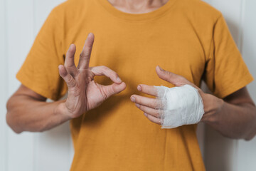 An individual wearing a yellow shirt with their left hand wrapped in a white bandage, possibly...