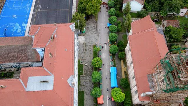 Drone footage of people walking down the street in town of Novi Becej in Serbia
