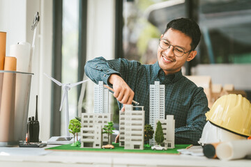 Asian people joyful person businessman engineer holding building model with wind turbines,...