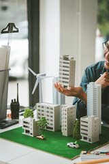 Asian people joyful person businessman engineer holding building model with wind turbines,...