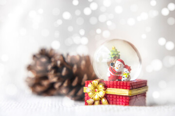 Christmas balls, Santa Claus in a Snow globe, and Pine cones on a white Cloth, set Against a Red Background and exquisite bokeh. New Year Celebration Atmosphere, about of Important day.
