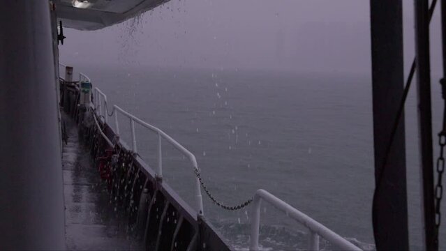 Water falls off ferry boat deck sailing in foggy rain storm