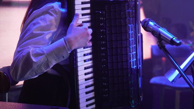 A girl plays the accordion in a subdued setting at an event.