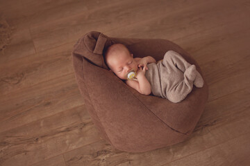 Newborn boy in a suit sleeps on a beanbag
