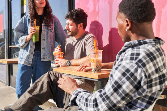 Friends drink boba at outdoor table 