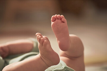 Close up of cute pink baby feet of little boy lying on back at home and practicing movement and...