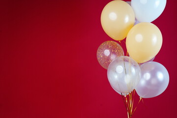 Light balloons - white, beige, transparent, pearl on a red background. Horizontal photo. Space for text