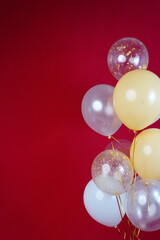 Fototapeta na wymiar Vertical photo of white and transparent balloons on red burgundy background. Space for text