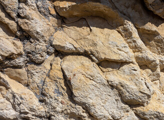 Natural stone walls are the entrance to a cave on a steep cliff of a mountain canyon
