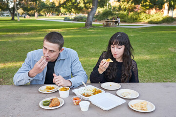 Couple eats Indian food at picnic table