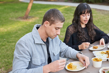 Couple eats Indian food at picnic table