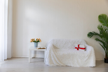 Fototapeta na wymiar Interior of a white room with a sofa, a window and flowers