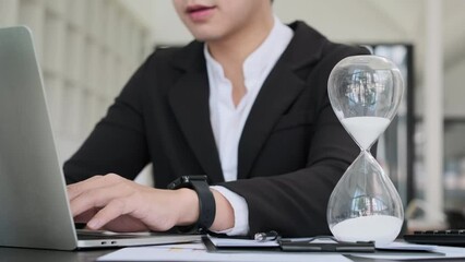 Slow motion shot of businessman flipping the hourglass and starts to work at office desk
