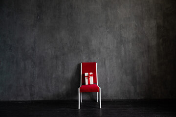One red chair with a gift in the interior of a dark room