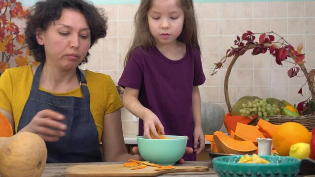 Thanksgiving Pumpkin Pie Cooking. Happy mother and child cooks pumpkin pie for harvest festival. Festive dinner cooking with family
