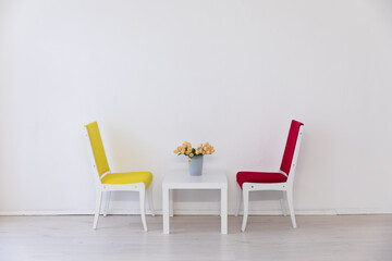 Yellow and red chair and table with flowers in white room interior