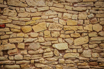 Close-up of Textured Stone Wall with Brickwork and Wood Detail. Textured stone wall with wood and brickwork patterns.