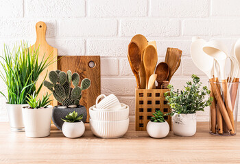 Beautiful kitchen background with set of cutting boards, wooden spoons, bowls. Front view. potted flowers. Eco-friendly kitchen