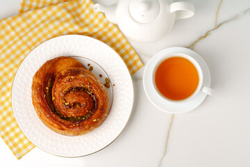 Top view of fresh baked bun with cup of tea on table